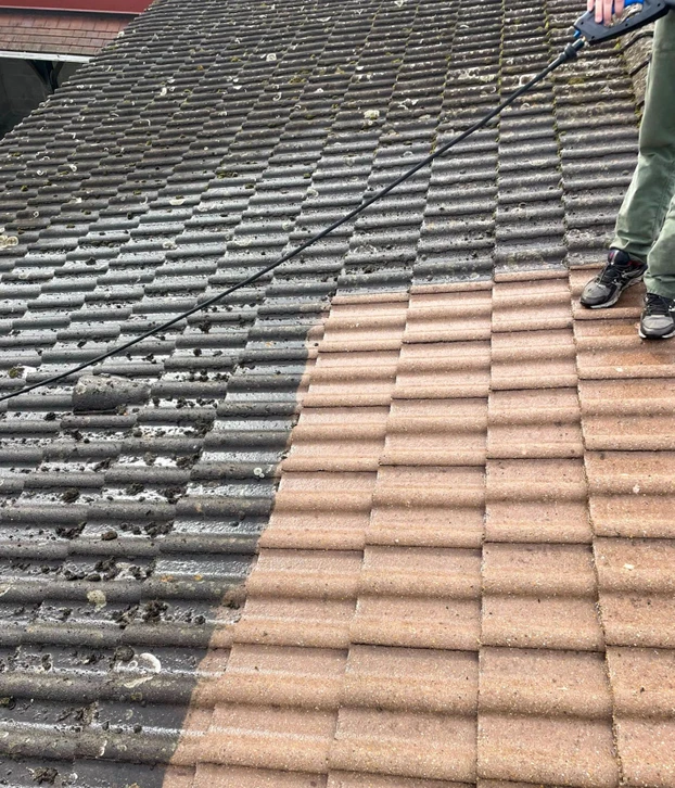 Deux couvreurs travaillent sur une toiture en pente, installant des liteaux métalliques